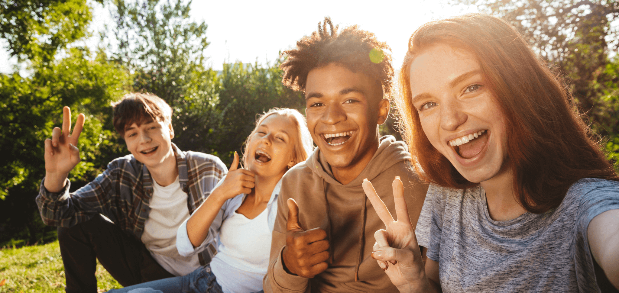 ©Drobot Dean - stock.adobe.com Jugendliche sitzen gut gelaunt auf einer Wiese