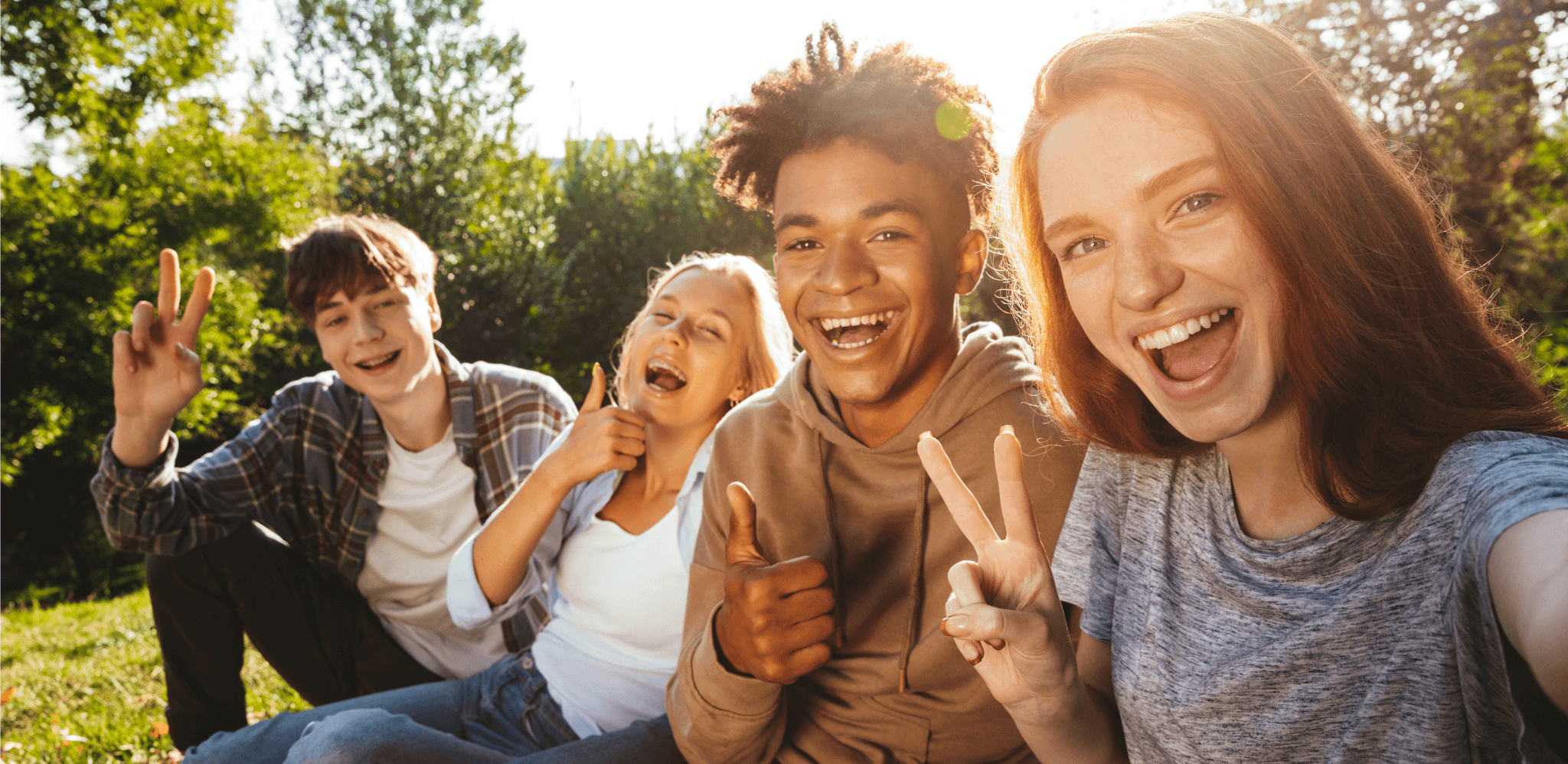 ©Drobot Dean - stock.adobe.com Jugendliche sitzen gut gelaunt auf einer Wiese