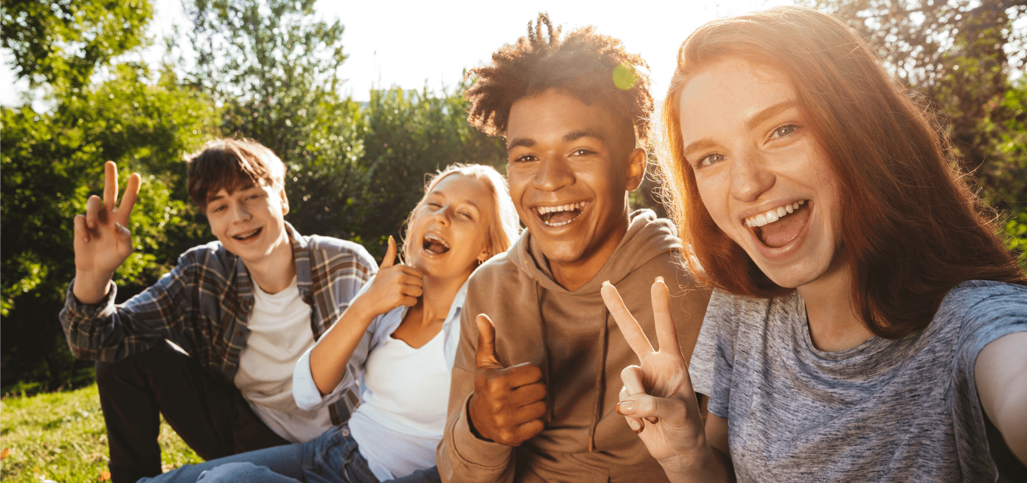 ©Drobot Dean - stock.adobe.com Jugendliche sitzen gut gelaunt auf einer Wiese